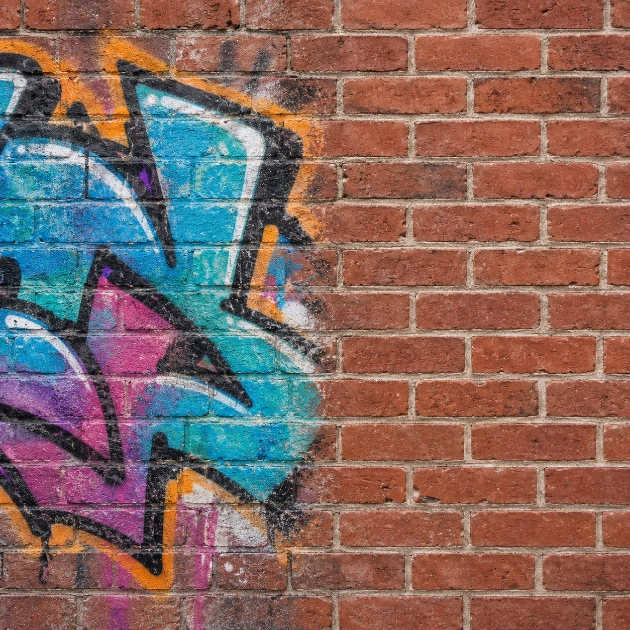 Graffiti à moitié effacé sur un mur en briques rouges